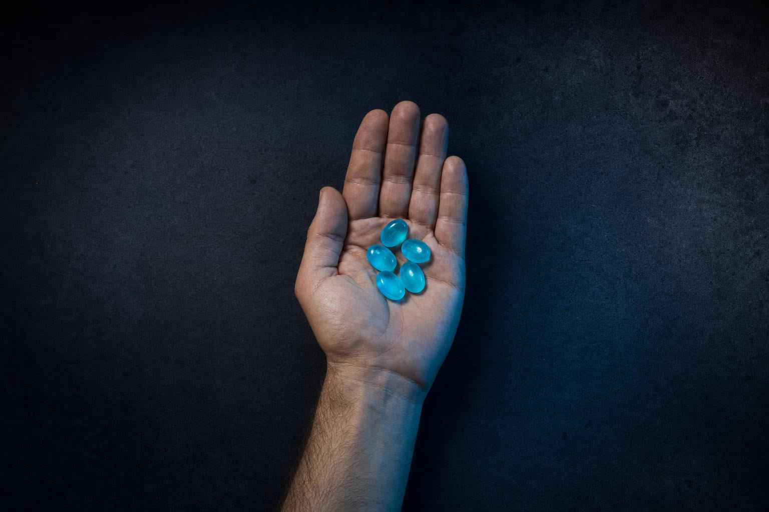 Una mano con cinco gomitas de creatina sobre la misma mesa, ya despejada